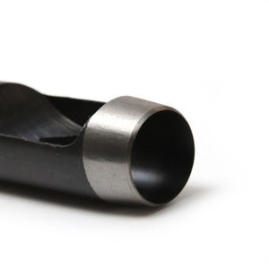 May include: Close-up of a black metal hole punch with a silver-colored cutting edge. The punch is designed to create round holes in materials like leather or paper.