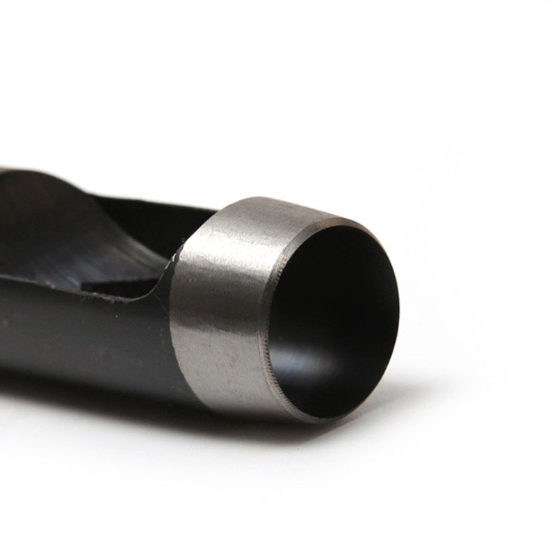 May include: Close-up of a black metal hole punch with a silver-colored cutting edge. The punch is designed to create round holes in materials like leather or paper.