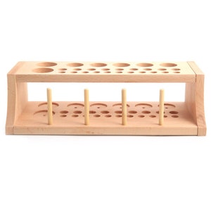 May include: A wooden organizer with multiple holes of different sizes for storing and organizing small items. The organizer has two levels and is made of natural wood.