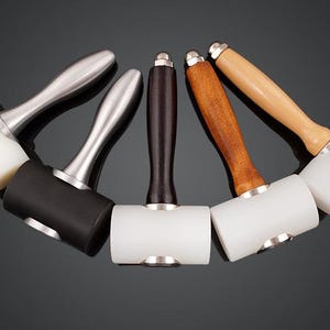 May include: Five leather working mallets with different colored handles. The mallets have white, black, and brown rubber heads.