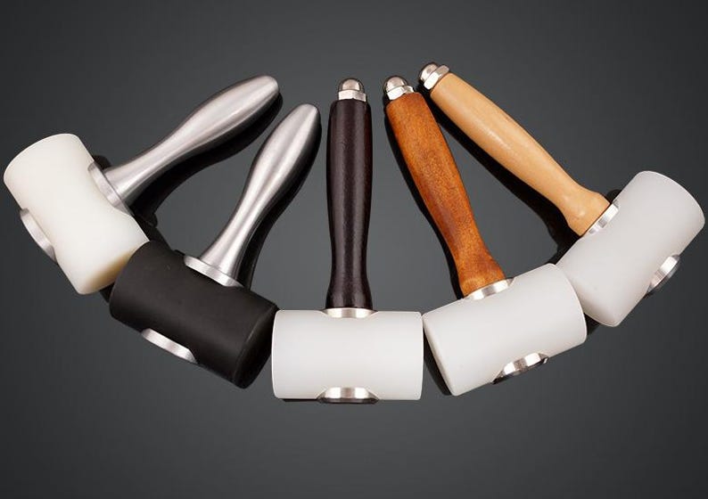 May include: Five leather working mallets with different colored handles. The mallets have white, black, and brown rubber heads.