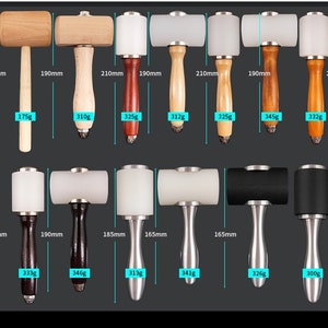 May include: Assortment of leather working hammers with wooden and metal handles. The hammers have white and black rubber heads. The hammers are labeled with their length and weight in millimeters and grams.