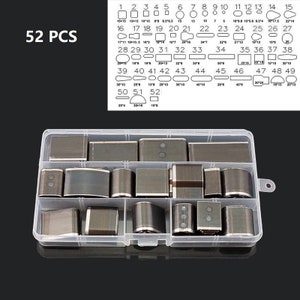 May include: A clear plastic organizer box containing 52 metal craft punches in various shapes and sizes. The sizes are labeled in inches. The text "52 PCS" is in the upper left corner. The punches are for leather, paper, or other craft materials.