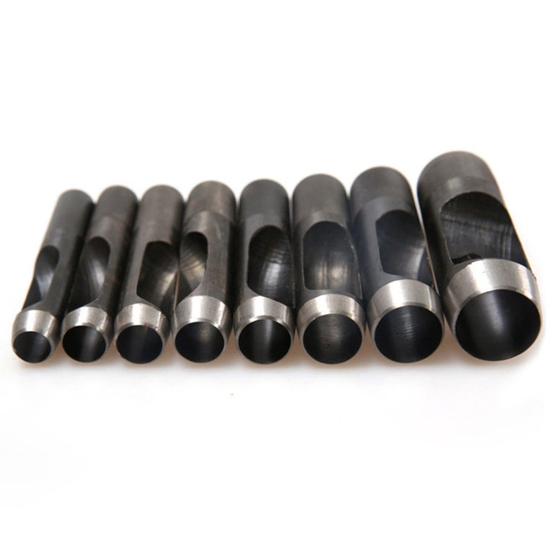 May include: A set of eight black metal hole punch tools with different sized round holes. The tools are arranged in a row from smallest to largest.