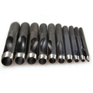 May include: A set of ten black metal hole punch tools with different sized round holes. The tools are arranged in order of size from largest to smallest.