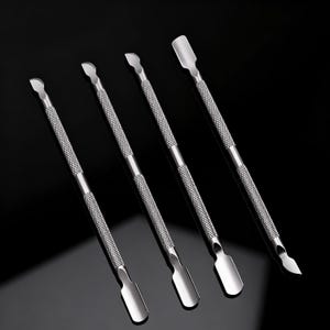 May include: Four silver-toned stainless steel cuticle pushers arranged diagonally. Each tool features a double-ended design with a flat, rounded spoon-shaped tip on one end and a curved, pointed blade on the other, connected by a textured, knurled grip.
