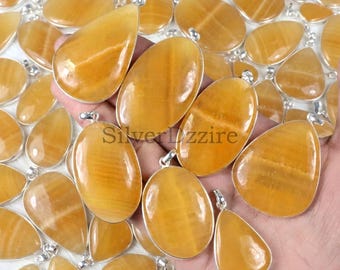 Può includere: Una collezione di ciondoli in calcite giallo dorato lucido, ognuno caratterizzato da una forma liscia a goccia o ovale, incastonata in una cornice di metallo color argento con un piccolo gancio sulla parte superiore. Le pietre mostrano venature.
