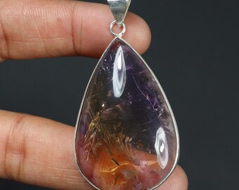 May include: A teardrop-shaped pendant featuring a polished amethyst gemstone with visible internal golden inclusions and purple hues, encased in a smooth silver-toned metal setting with a triangular bail at the top for attachment to a chain.