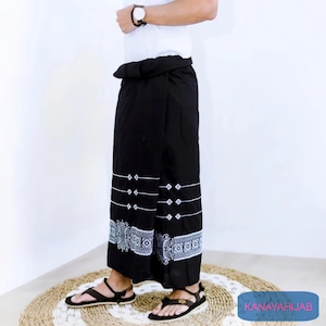 May include: A black sarong with white geometric patterns. The sarong is tied at the waist and has a long, flowing skirt.