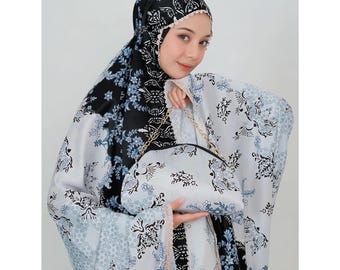 May include: A white and black prayer rug with a floral pattern. The rug has a matching bag with a gold chain.