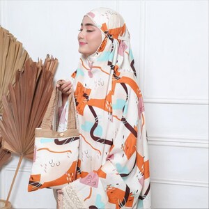 May include: A white and orange patterned headscarf with a brown tote bag. The tote bag has a brown strap and a white and orange patterned design.