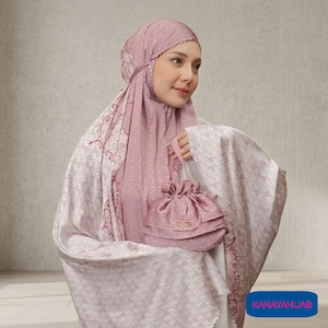 May include: A light pink prayer garment set with a matching drawstring bag. The set includes a head covering and a long, flowing robe, both featuring a delicate floral pattern. The bag has a small rectangular tag. The text "KANAYAHIJAB" is in a blue rectangle.