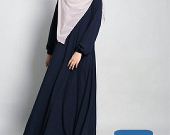 Puede incluir: Un vestido largo de maxi azul marino con mangas largas y cintura fruncida. El vestido se lleva con un pañuelo de cabeza rosa claro. El texto "KANAYAHIJAB" es visible en la esquina inferior derecha de la imagen.