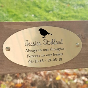 May include: Gold oval memorial plaque with a black silhouette of a bird and the text "Jessica Stoddard, Always in our thoughts, Forever in our hearts, 06-11-45 - 13-05-18".
