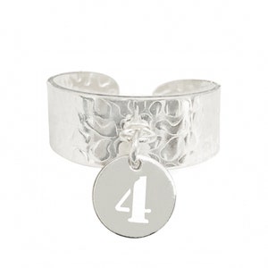 May include: Silver ring with a hammered band and a charm with the number 4.