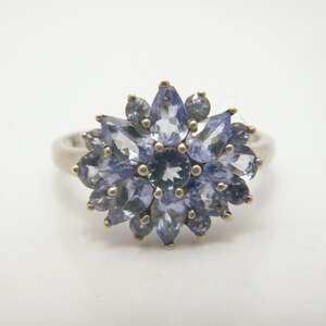 Peut inclure: Une bague en argent avec un groupe de pierres précieuses bleu clair disposées en forme de fleur.