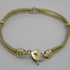 May include: A gold chain bracelet with a heart-shaped padlock clasp. The chain is made of two strands of braided metal.