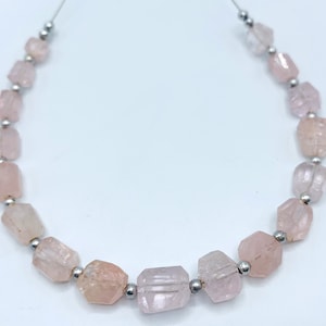 Pode incluir: Um fio de contas facetadas de quartzo rosa claro. As contas são enfiadas em um fio fino de cor prateada e separadas por pequenas contas de cor prateada. As pedras preciosas têm uma aparência ligeiramente translúcida.