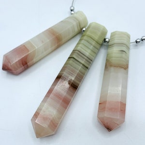 May include: Three faceted crystal pendants in pink, green, and cream. Each pendant is rectangular with a pointed end and strung on a silver wire with small beads. The crystals have a layered, banded appearance.