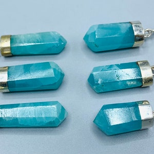 May include: Six blue-green crystal pendants with silver-colored metal caps and loops. The pendants are hexagonal in shape and have a polished, faceted appearance. The background is a light gray color.