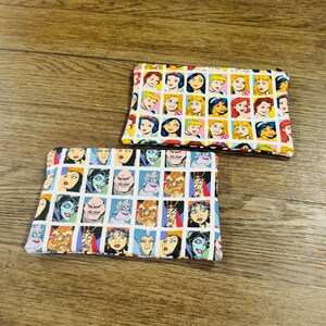 May include: Two fabric pouches with a white background and a repeating pattern of cartoon faces. One pouch features Disney princesses, the other features Disney villains.