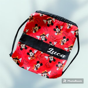 May include: Red drawstring bag with a black band and the name Luca printed in white. The bag is covered in a repeating pattern of Mickey Mouse heads.
