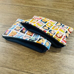 May include: Three zippered pouches with a white background and colorful images of Disney princesses and villains. The pouches are made of fabric and have a black zipper.