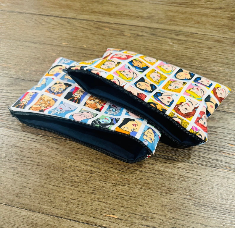 May include: Three zippered pouches with a white background and colorful images of Disney princesses and villains. The pouches are made of fabric and have a black zipper.