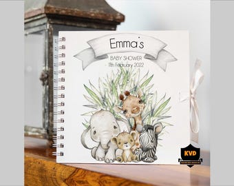 Puede incluir: Un libro de visitas para baby shower con espiral, con una ilustración de acuarela de una jirafa, un elefante, un león y una cebra. La portada dice "Emma's BABY SHOWER 11th February 2022" en una pancarta. Una cinta crema cierra el libro.