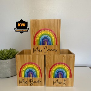 Pu&ograve; includere: Tre portapenne in bamb&ugrave; con un colorato design arcobaleno. Ogni portapenne ha un nome diverso: Miss Cannons, Miss Bowden e Miss K. L'arcobaleno presenta colori rosso, arancione, giallo, verde, blu e viola.
