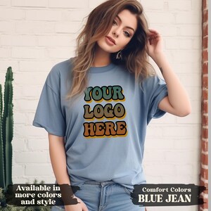 Flat lay of personalized t-shirt with custom uploaded image and text, perfect for matching group shirts for birthdays, girls’ trips, company branding, or school spirit events. DTG printing ensures durable, detailed results on soft cotton fabric. Available from infant to 3XL in Comfort Colors, Softstyle, or sweatshirt formats. Great gift for family, friends, or coworkers.
