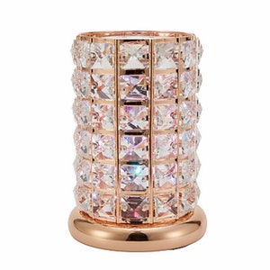 May include: A rose gold candle holder with a cylindrical design. The holder is adorned with clear crystal embellishments.