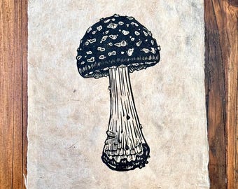 May include: Black and white linocut print of a fly agaric mushroom on a beige paper background. The print is signed and numbered "1/9 Fly Agaric E.W. 2020".