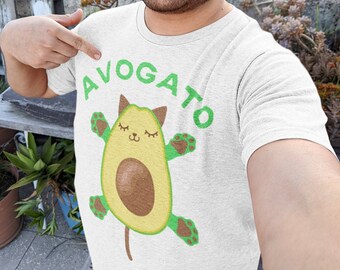 May include: A white t-shirt with a green avocado design. The avocado has a cat face and paws. The word "AVOGATO" is written in green letters above the avocado.