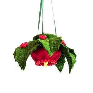 Puede incluir: Adorno navideño hecho a mano con forma de baya de acebo. El adorno presenta una baya roja con detalles de cuentas rojas, hojas de fieltro verde y una cinta verde para colgar. El adorno tiene un estambre amarillo.