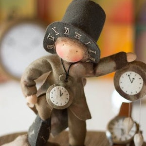 Könnte beinhalten: Eine skurrile Filzpuppe, die einen Zeitwächter darstellt und einen Zylinder mit römischen Ziffern trägt. Die Puppe hat einen Uhrenanhänger und hält eine Uhr in der Hand. Die Puppe trägt einen braunen Mantel und eine Hose.