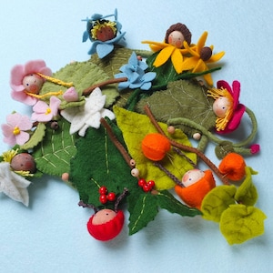 May include: A felt craft set featuring a variety of felt flowers, leaves, and figures. The figures are made of felt and have painted faces. The set includes a variety of colours, including green, yellow, red, blue, and pink.