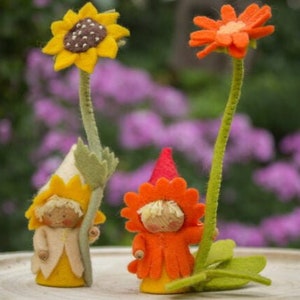 May include: Two felt flower people with yellow and orange flowers. The flower people are holding felt flowers with green stems.