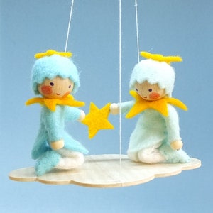 May include: A wooden mobile with two blue felt angels holding a yellow star. The angels have yellow halos and are suspended from a wooden cloud.