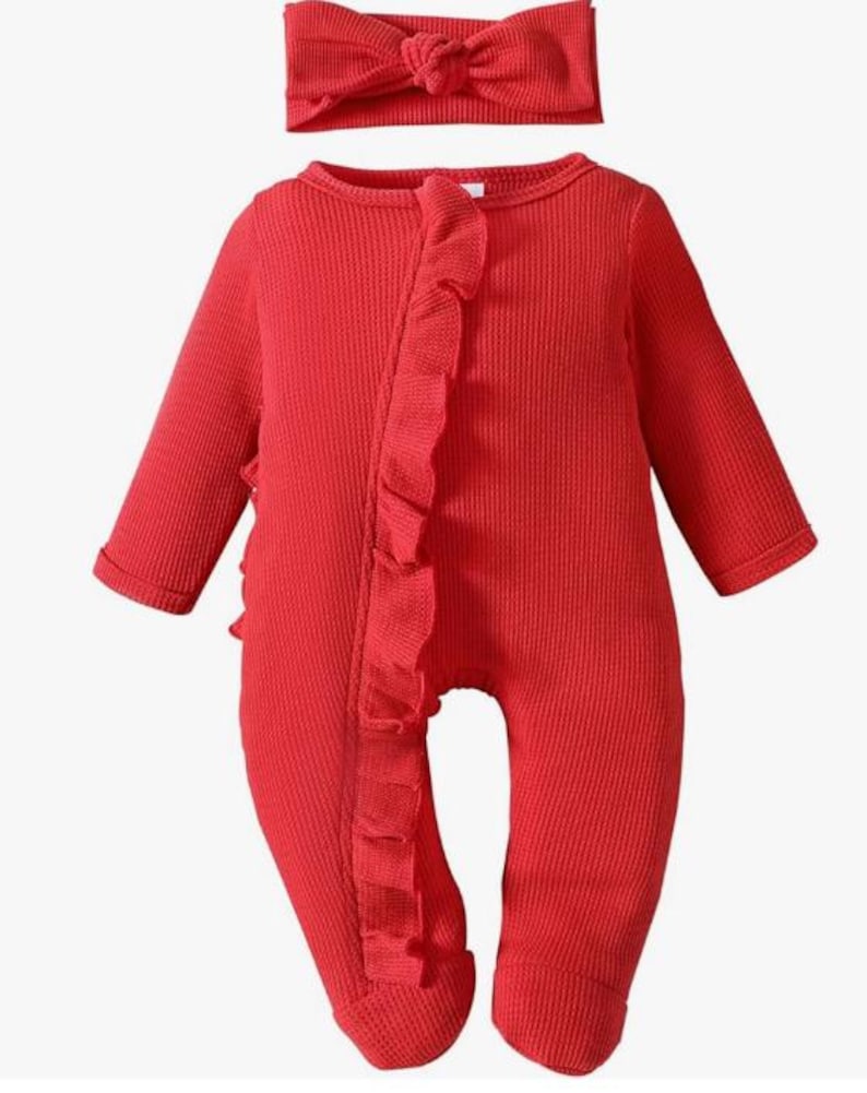 Puede incluir: Un conjunto de ropa de beb&eacute; rojo, que incluye un pelele de manga larga y una diadema a juego. El pelele presenta un ribete con volantes en la parte delantera y una tela de punto texturizada. La diadema tiene un detalle de lazo. El conjunto est&aacute; dise&ntilde;ado para beb&eacute;s.