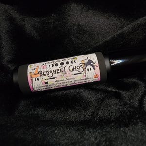 May include: A black roll-on bottle with a white label that says "LOVESICK WITCHERY BEDSHEET GHOST" and lists the ingredients: "Almond, honey, coconut milk, rice powder, marshmallow, milky vanilla, white soap, musk, and orris root."