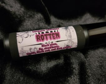 Può includere: Un flacone nero roll-on con un'etichetta bianca che dice "Lovesick Witchery" e "Rotten". L'etichetta elenca anche le note olfattive: "Prugna nera, fico, fragola, legno, oud nero e ambra scura."