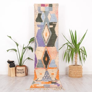 May include: A long, narrow rug with a colorful geometric pattern in shades of blue, purple, orange, and green. The rug has a fringe on both ends.