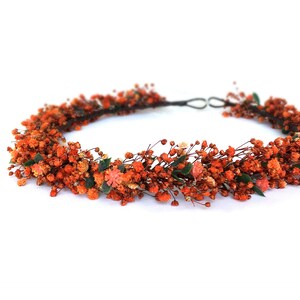 May include: A floral crown made of dried orange flowers and greenery. The crown is made on a wire base and is perfect for a wedding or special occasion.