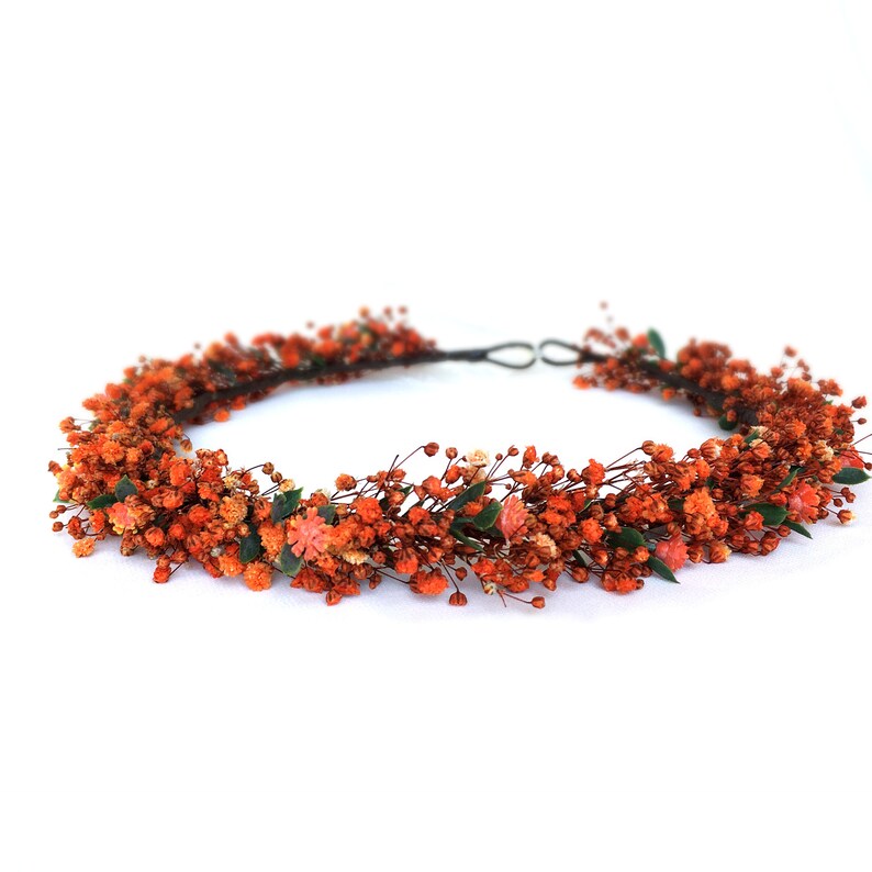 May include: A floral crown made of dried orange flowers and greenery. The crown is made on a wire base and is perfect for a wedding or special occasion.