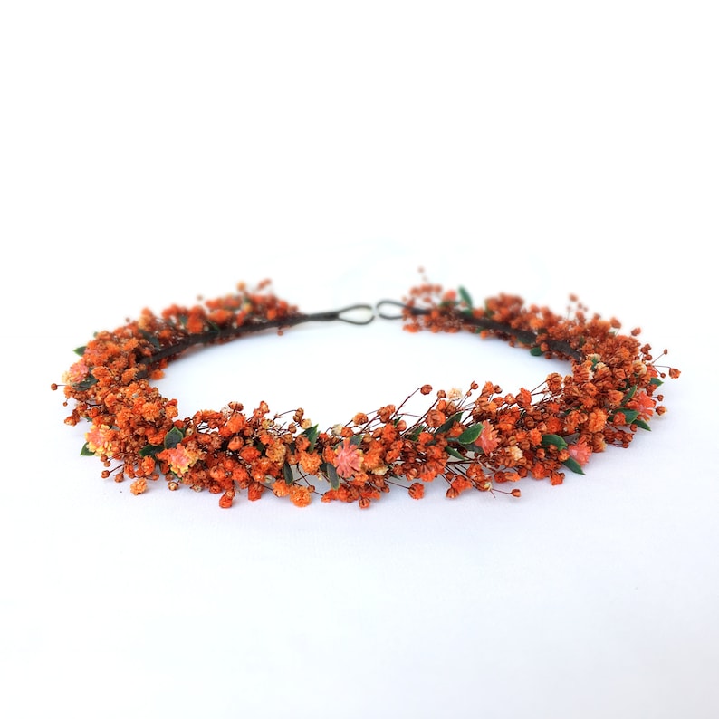 May include: A floral crown made of dried orange flowers and greenery. The crown is made on a wire base and is perfect for a wedding or other special occasion.