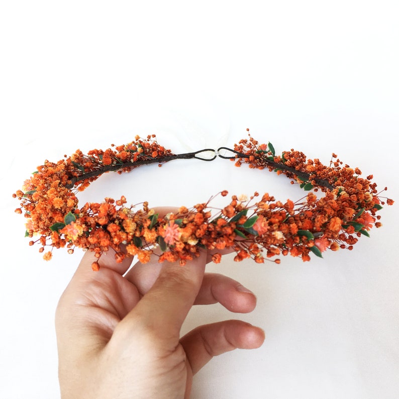 May include: A floral crown made of dried orange flowers and greenery. The crown is made on a wire base and is perfect for a wedding or special occasion.