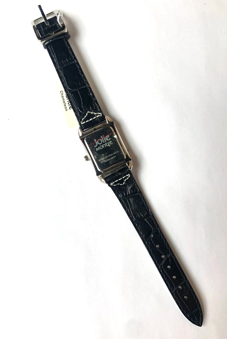 Puede incluir: Un reloj de cuero negro con una esfera rectangular plateada. La correa del reloj tiene una textura de cocodrilo. La esfera del reloj tiene las palabras "Jolie Montre" y "Stainless Steel Back Japan Movt". Una etiqueta blanca est&aacute; adherida a la correa.