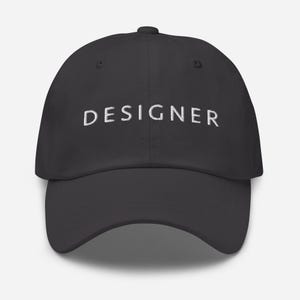 May include: A dark gray baseball cap with the word "DESIGNER" embroidered in white on the front.