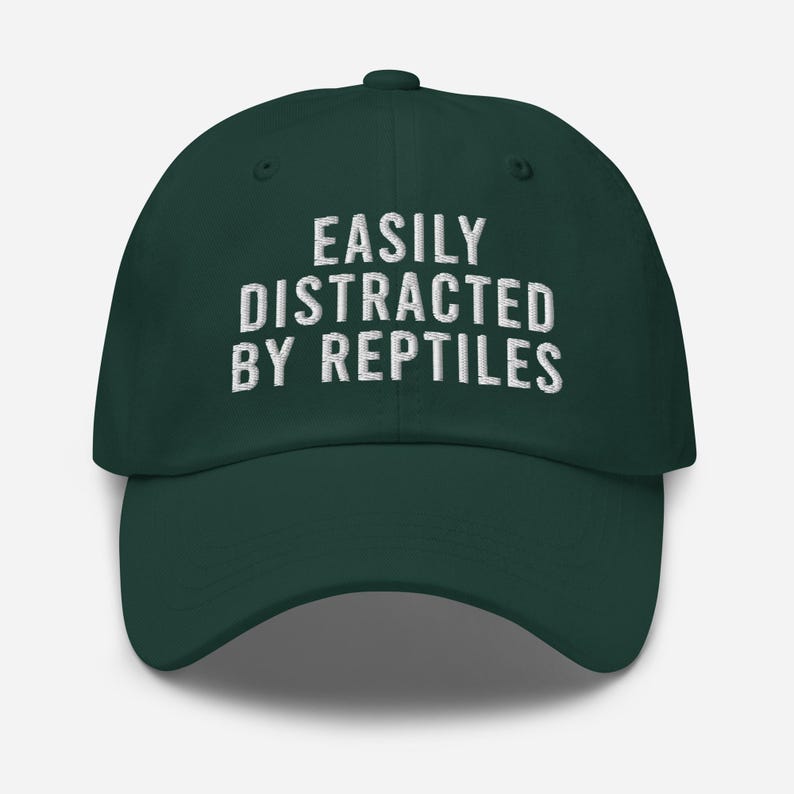 May include: A dark green baseball cap with white embroidered text that reads "EASILY DISTRACTED BY REPTILES".